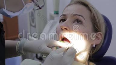 女牙医给女病人治疗牙齿。 口腔医生治疗病人牙齿`龋病。 牙科口腔卫生